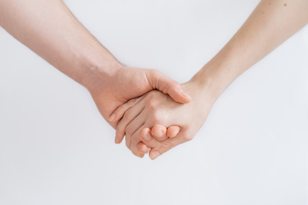 Two hands holding each other, symbolizing support and hope, representing the transformative impact of neurofeedback for mental health in 2025.